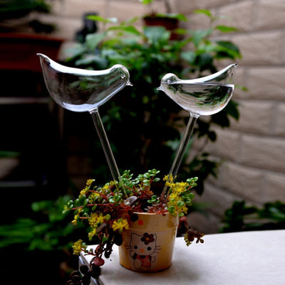 Glass bird self-watering device in a potted plant